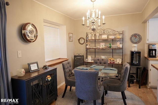 dining area featuring crown molding, a notable chandelier, and light wood-type flooring