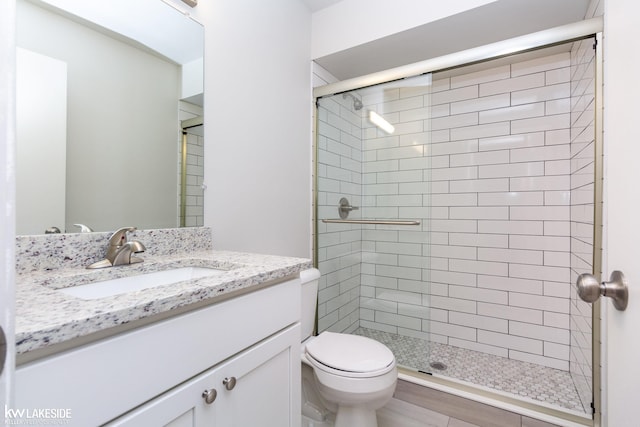 bathroom featuring vanity, toilet, and an enclosed shower