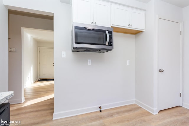 kitchen with white cabinetry, light stone countertops, and light hardwood / wood-style floors