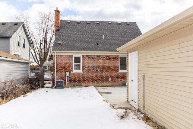 snow covered house featuring central air condition unit