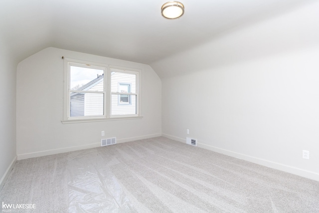 bonus room with vaulted ceiling and light colored carpet