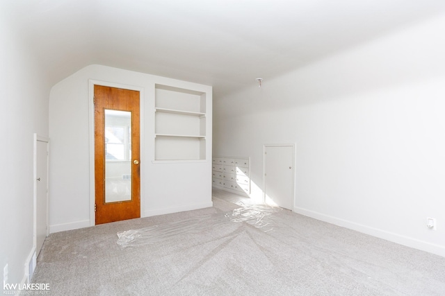 carpeted empty room featuring lofted ceiling