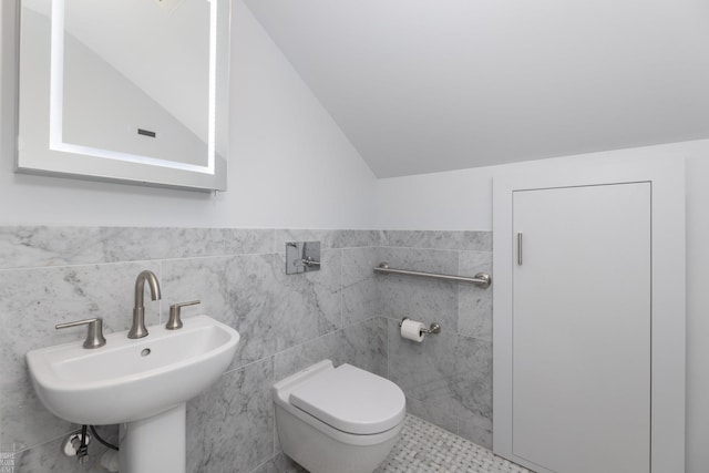 bathroom with lofted ceiling, sink, tile walls, and toilet