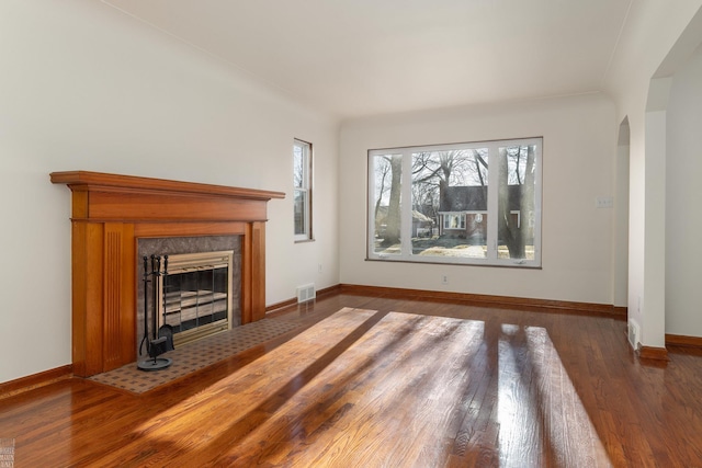 unfurnished living room featuring a premium fireplace and dark hardwood / wood-style flooring