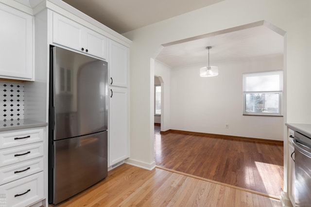 kitchen with stainless steel appliances, white cabinets, light wood-type flooring, and decorative light fixtures