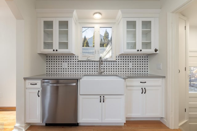 kitchen with stainless steel dishwasher, sink, decorative backsplash, and white cabinets