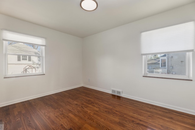 spare room with dark wood-type flooring and a healthy amount of sunlight