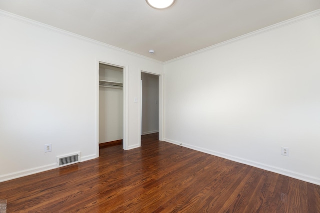 unfurnished bedroom with dark hardwood / wood-style flooring, crown molding, and a closet