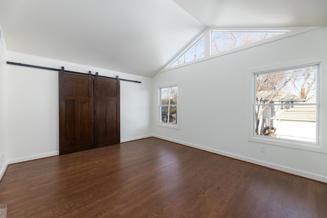 unfurnished bedroom with a barn door, dark hardwood / wood-style flooring, and vaulted ceiling