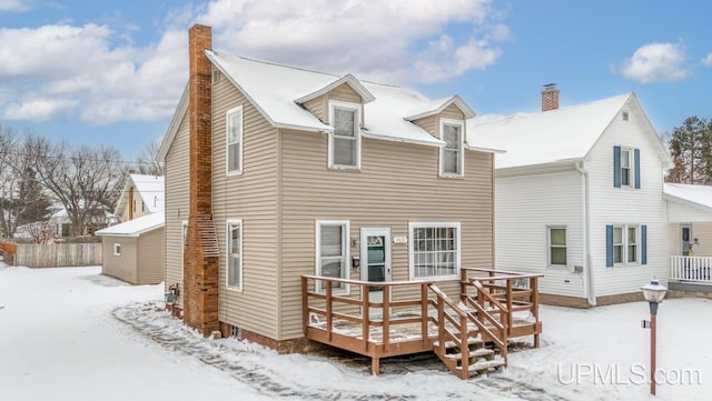 snow covered rear of property featuring a shed and a deck