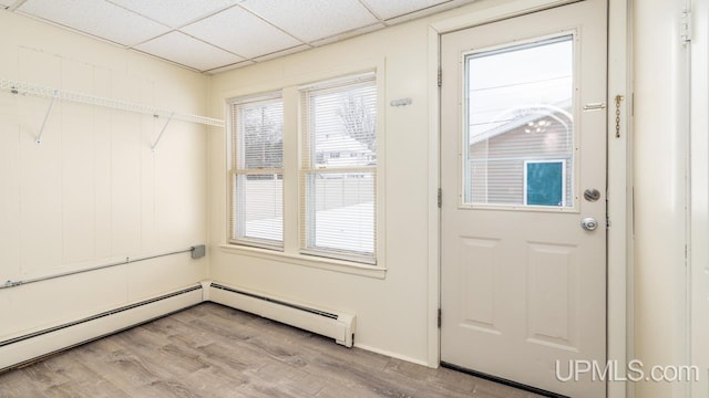 doorway with a baseboard radiator, light wood-type flooring, and a drop ceiling