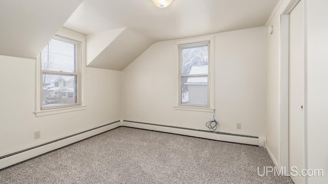 additional living space featuring baseboard heating, light colored carpet, a healthy amount of sunlight, and vaulted ceiling