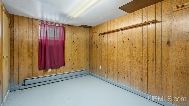 empty room with a baseboard heating unit and wooden walls