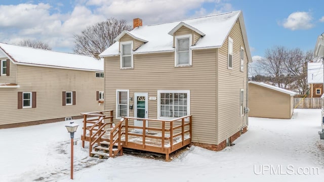 snow covered rear of property with a deck