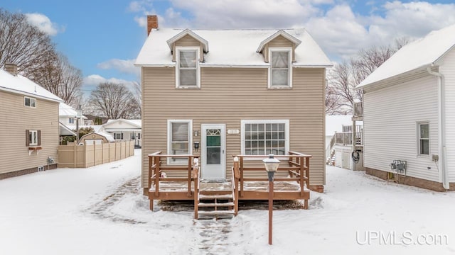 snow covered back of property featuring a deck