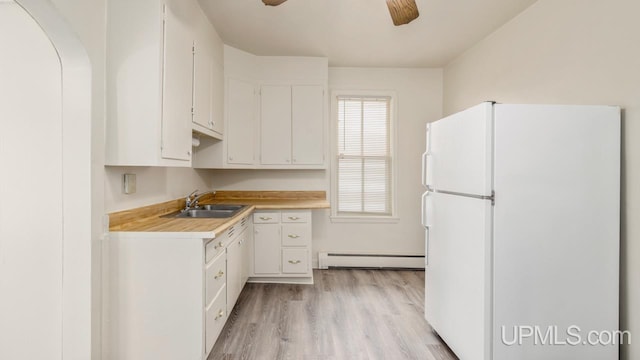 kitchen featuring sink, a baseboard heating unit, white refrigerator, light hardwood / wood-style floors, and white cabinets