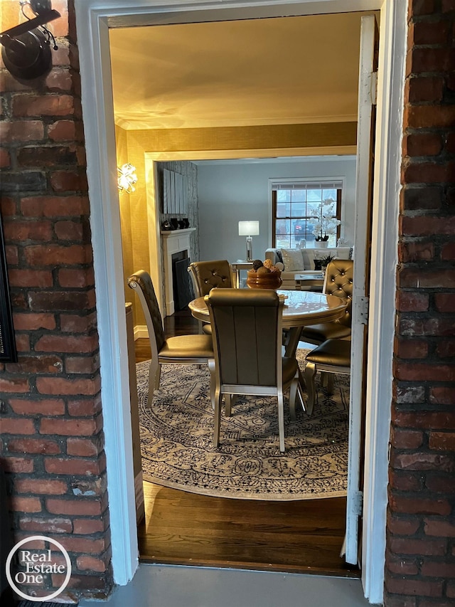 interior space with hardwood / wood-style flooring, brick wall, and a fireplace