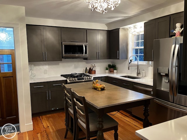 kitchen featuring sink, hardwood / wood-style flooring, backsplash, stainless steel appliances, and a wealth of natural light