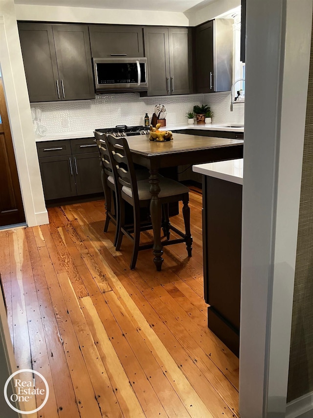 kitchen featuring sink, light wood-type flooring, and decorative backsplash