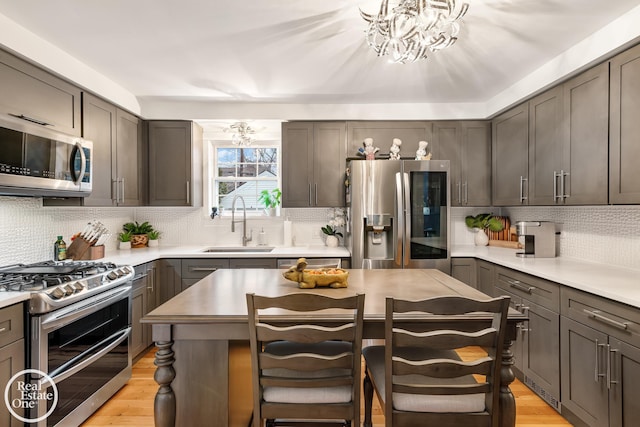 kitchen with tasteful backsplash, stainless steel appliances, light hardwood / wood-style floors, and sink