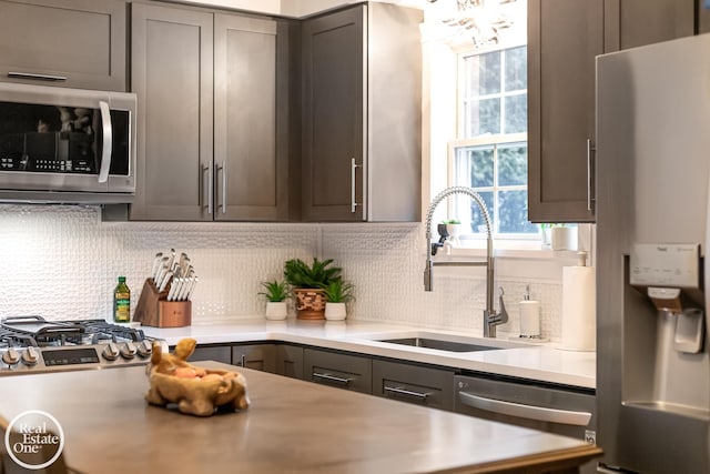 kitchen with tasteful backsplash, stainless steel appliances, gray cabinets, and sink