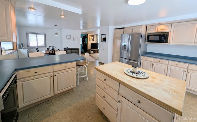 kitchen featuring a kitchen island, wood counters, decorative light fixtures, a kitchen bar, and black appliances