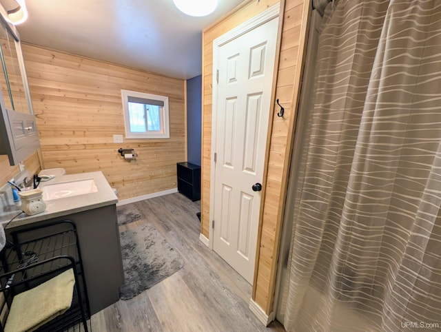 bathroom featuring vanity, hardwood / wood-style floors, and wood walls