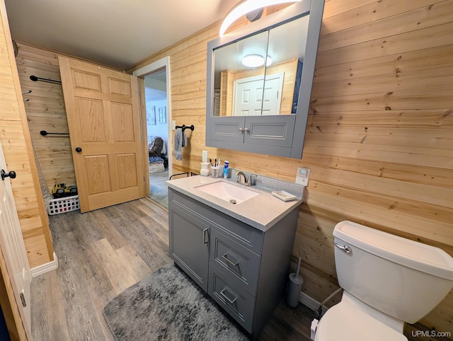 bathroom with vanity, toilet, hardwood / wood-style floors, and wood walls