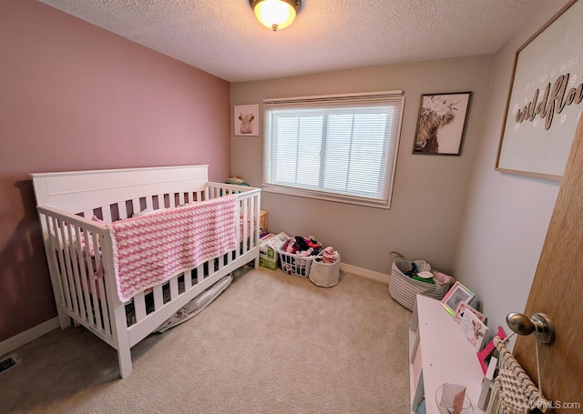 bedroom featuring a crib, a textured ceiling, and carpet