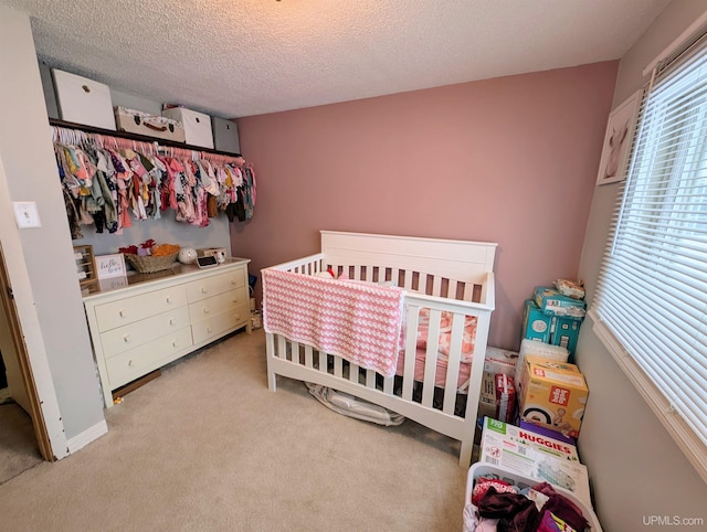 carpeted bedroom featuring a nursery area and a textured ceiling