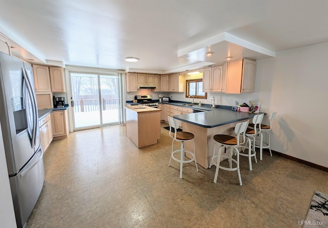 kitchen featuring sink, a breakfast bar area, a center island, light brown cabinets, and stainless steel appliances