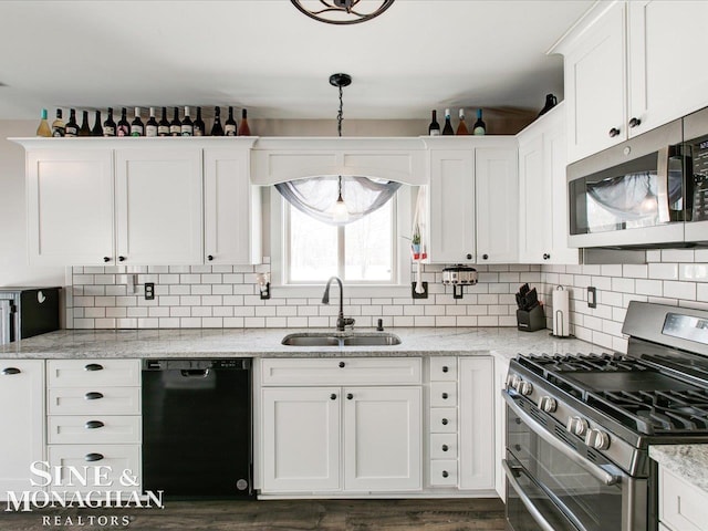 kitchen with white cabinetry, stainless steel appliances, light stone countertops, and sink