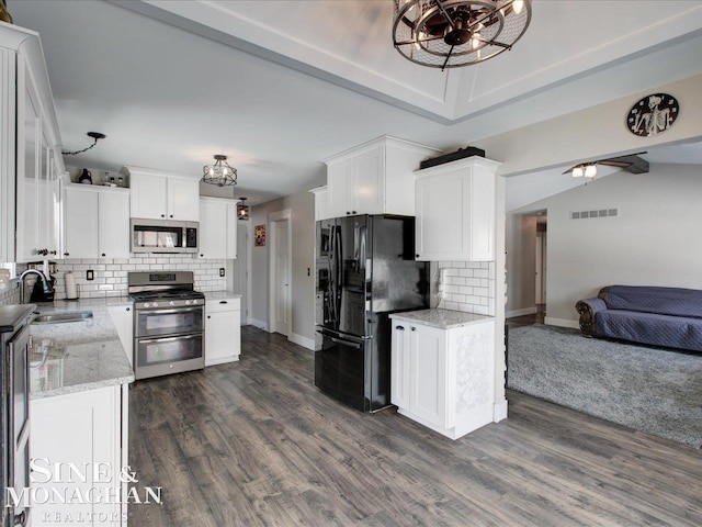 kitchen featuring appliances with stainless steel finishes, white cabinetry, sink, dark hardwood / wood-style flooring, and light stone countertops