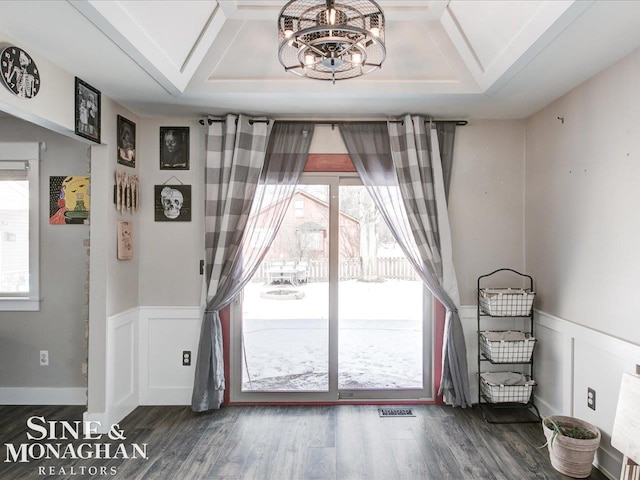 doorway to outside with plenty of natural light, a tray ceiling, dark hardwood / wood-style flooring, and a notable chandelier