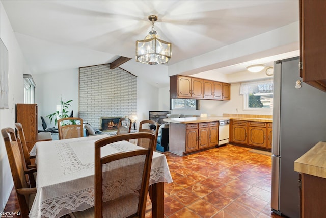 dining room with a fireplace, lofted ceiling with beams, and a chandelier