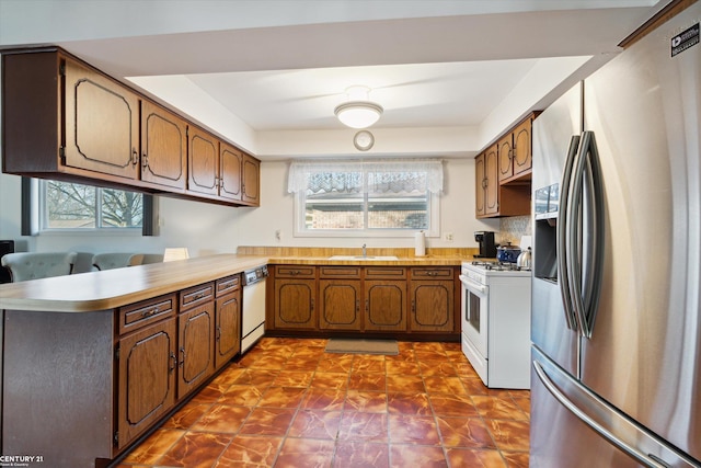 kitchen featuring white appliances, kitchen peninsula, sink, and backsplash