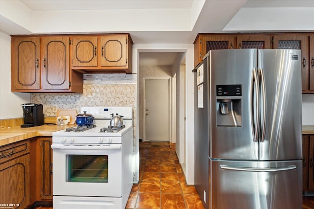 kitchen featuring decorative backsplash, stainless steel fridge, and gas range gas stove