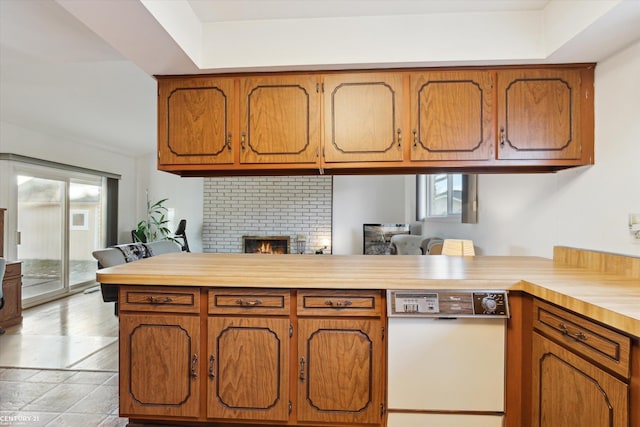 kitchen with a fireplace, dishwasher, and kitchen peninsula