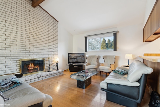 living room with a brick fireplace, high vaulted ceiling, light hardwood / wood-style floors, and beamed ceiling