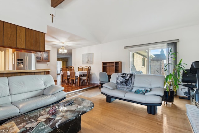 living room with an inviting chandelier, vaulted ceiling with beams, and light hardwood / wood-style floors