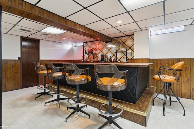 bar featuring a paneled ceiling and wood walls