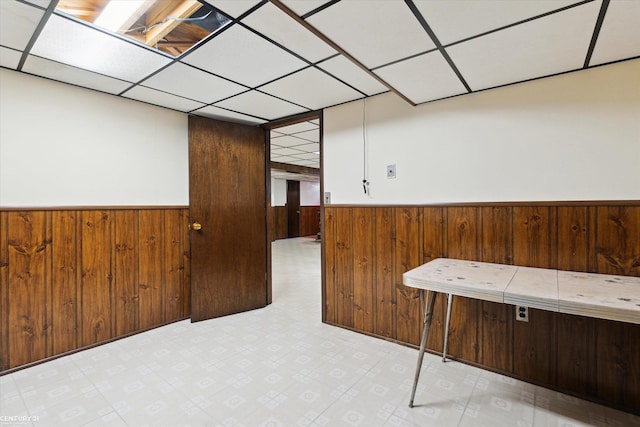 interior space with a paneled ceiling and wood walls