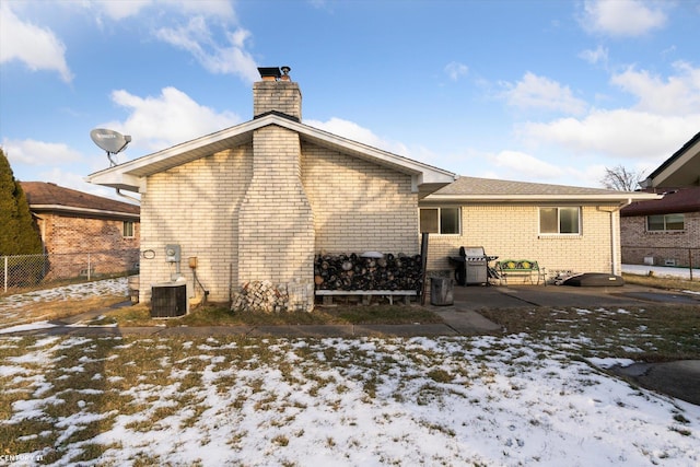 snow covered back of property featuring cooling unit