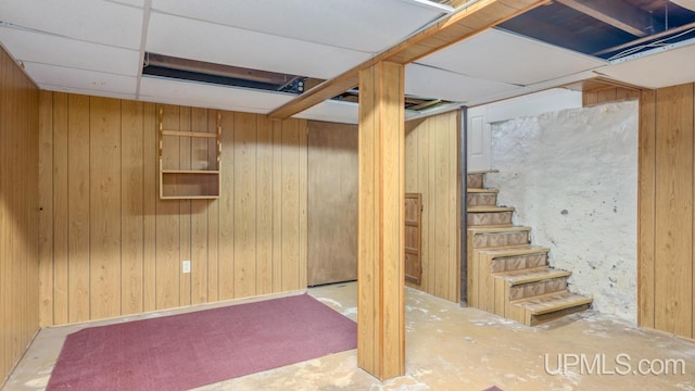 basement with a drop ceiling and wooden walls