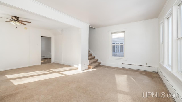 carpeted empty room with crown molding and a baseboard heating unit