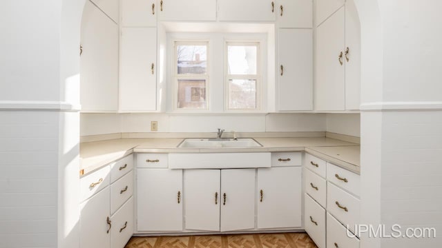 kitchen featuring white cabinetry, sink, and light parquet floors