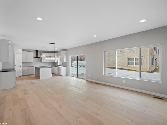 unfurnished living room featuring sink and light hardwood / wood-style floors