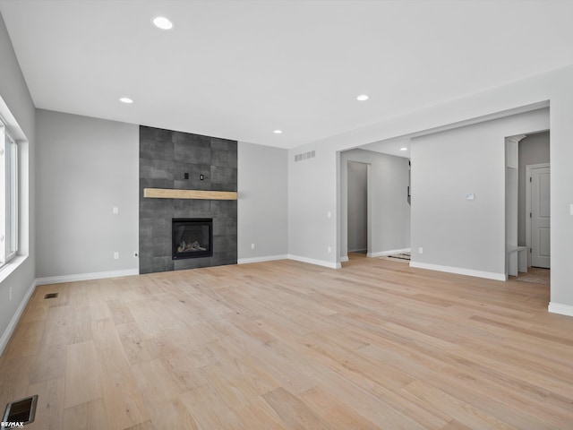 unfurnished living room featuring a tile fireplace and light wood-type flooring