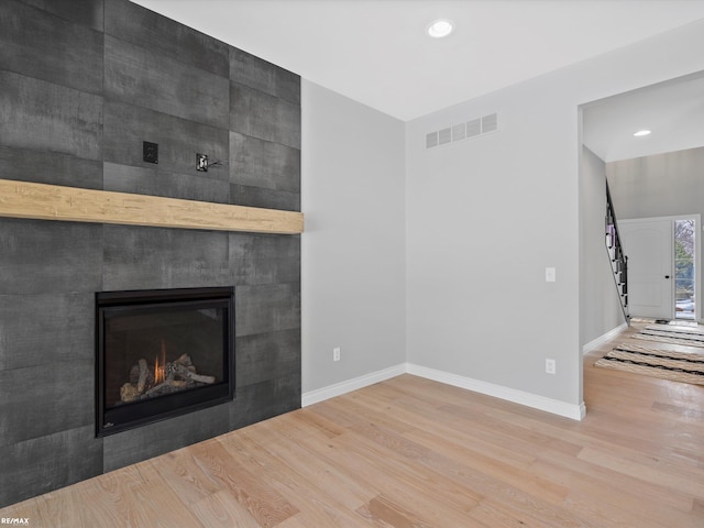 unfurnished living room with a tiled fireplace and hardwood / wood-style floors