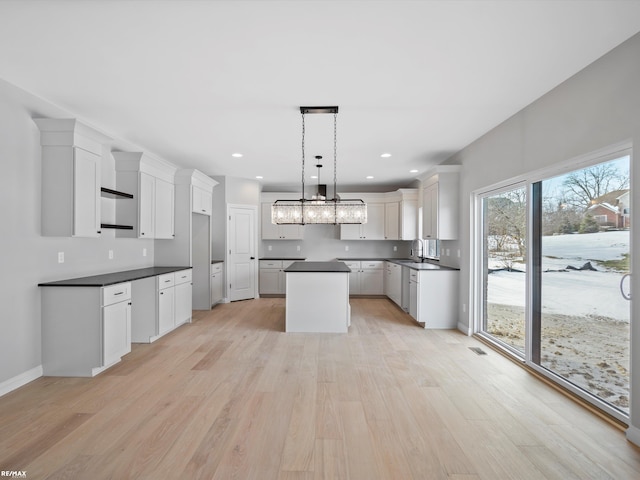 kitchen featuring sink, white cabinetry, a center island, light hardwood / wood-style floors, and decorative light fixtures